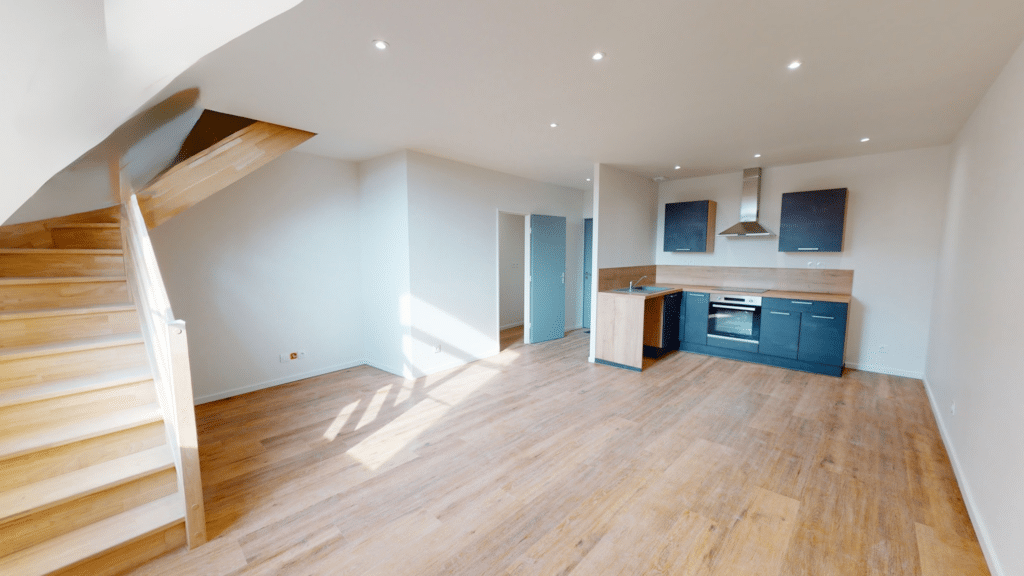 Salon moderne avec escalier en bois et cuisine ouverte dans une grange transformée en logement dans la Somme