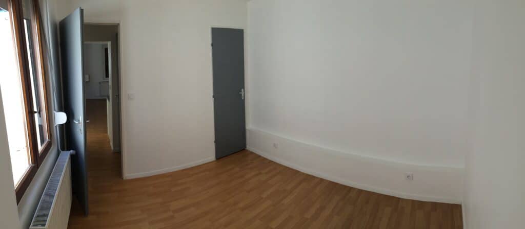 Chambre rénovée dans une maison de ville à Moreuil avec parquet, murs blancs et porte contemporaine