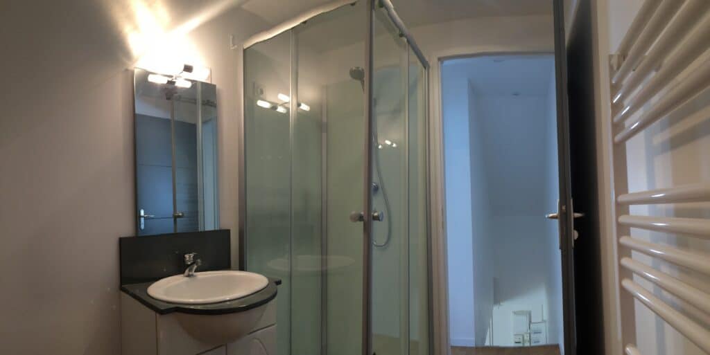 Salle de bain rénovée avec cabine de douche en verre, vasque moderne et radiateur sèche-serviettes dans une maison à Moreuil
